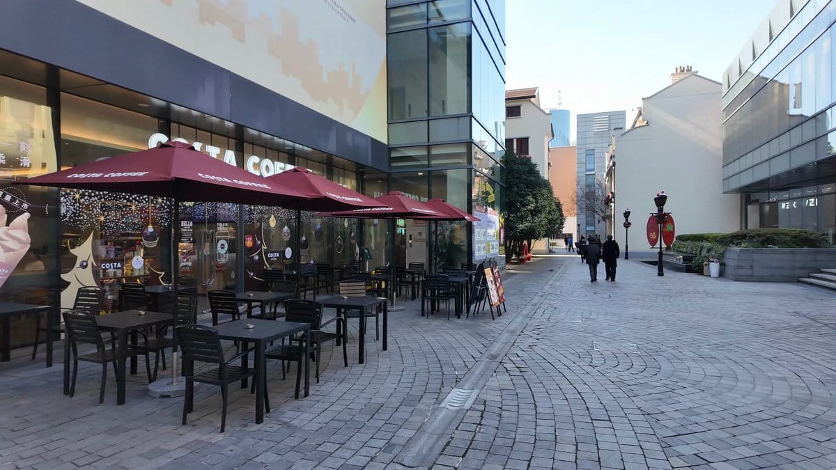 A cafe terrace under red parasols, chairs stacked