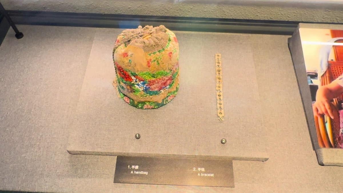 A decorated handbag displayed alone in a glass