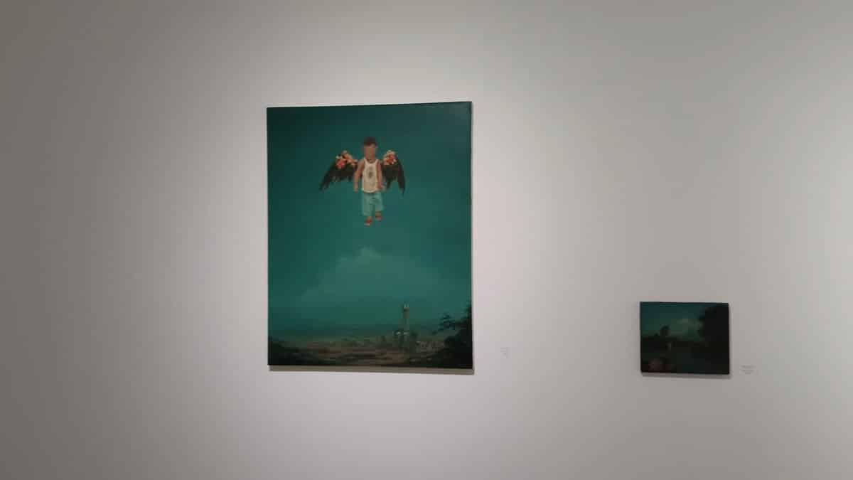 A green-toned painting hanging alone on a grey