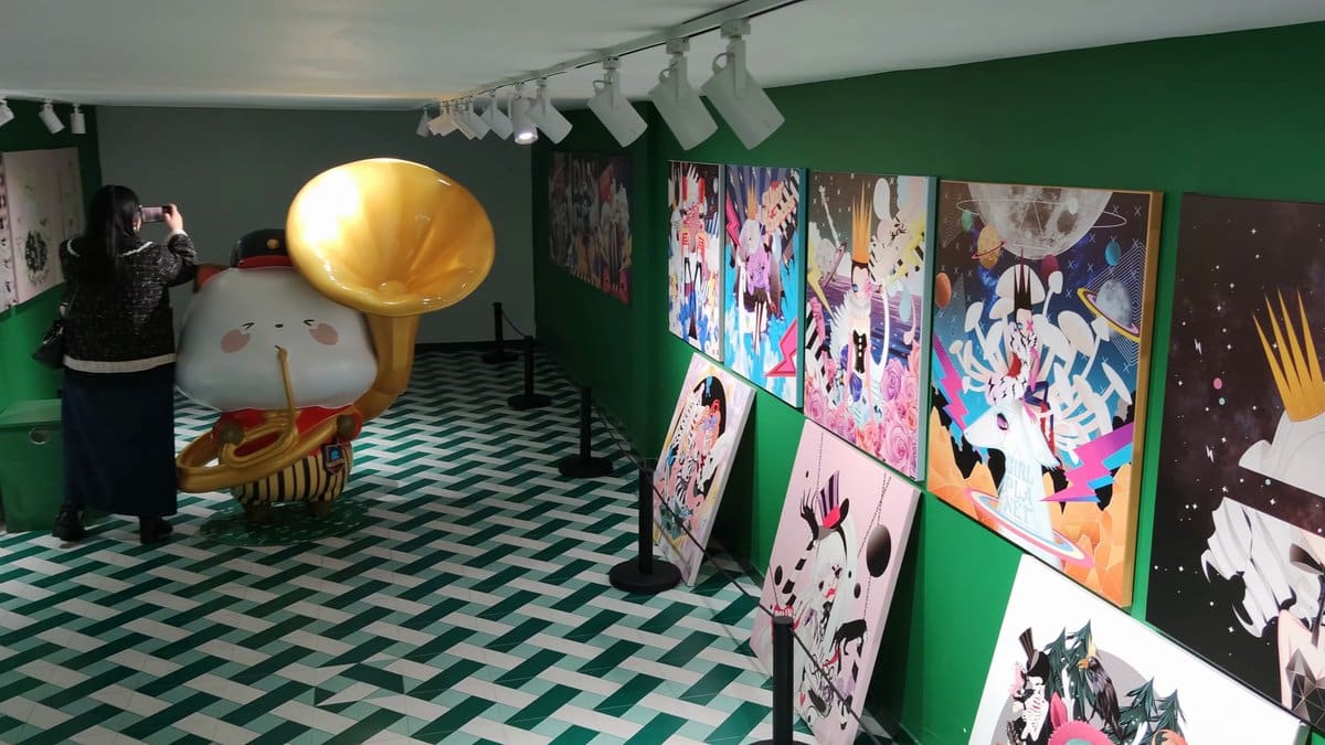 A green-walled gallery, bright canvases propped in a