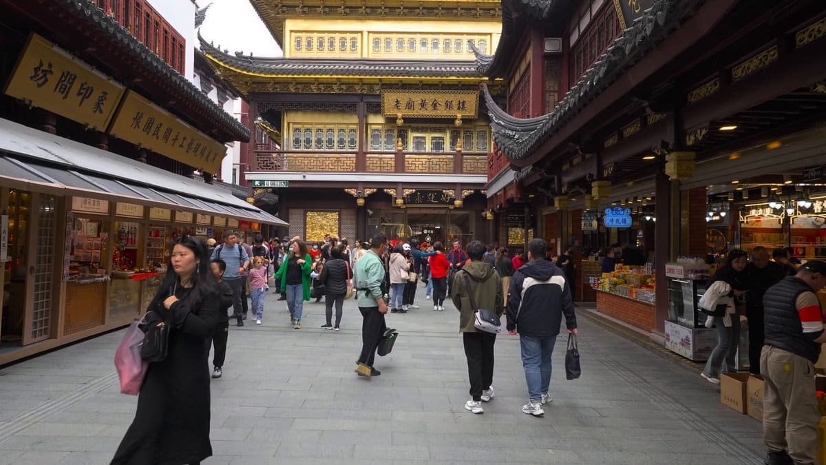 A lane of shopfronts under fabric awnings, shoppers