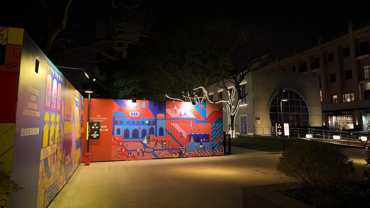 A long red hoarding printed with illustrated buildings