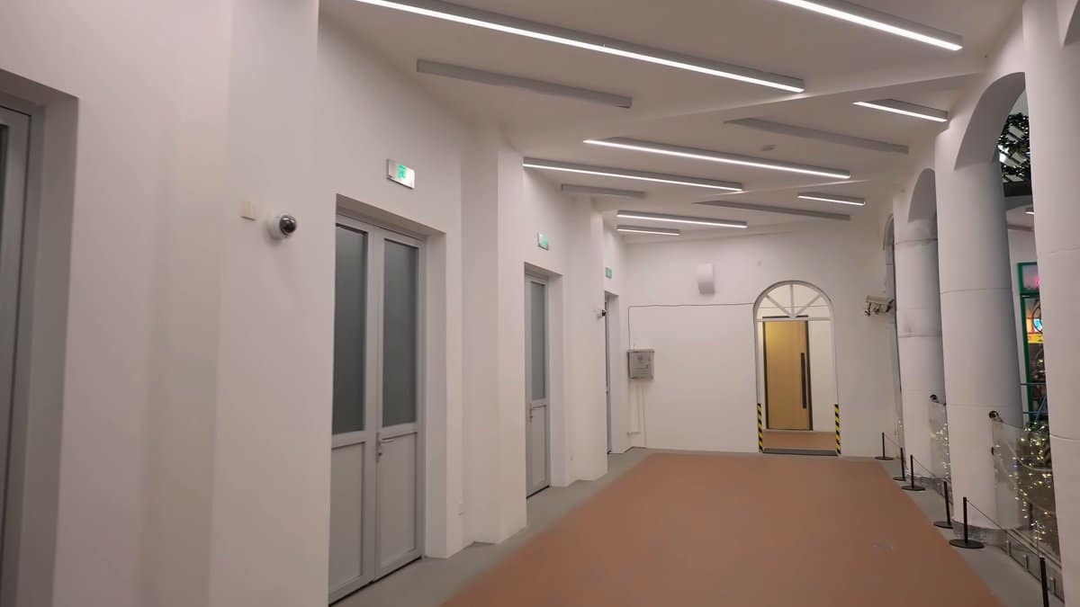 A plain white service corridor with doors along