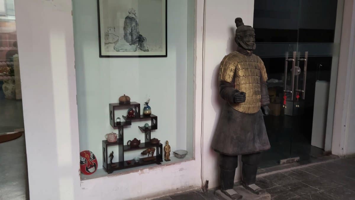 A terracotta warrior figure standing beside a doorway,