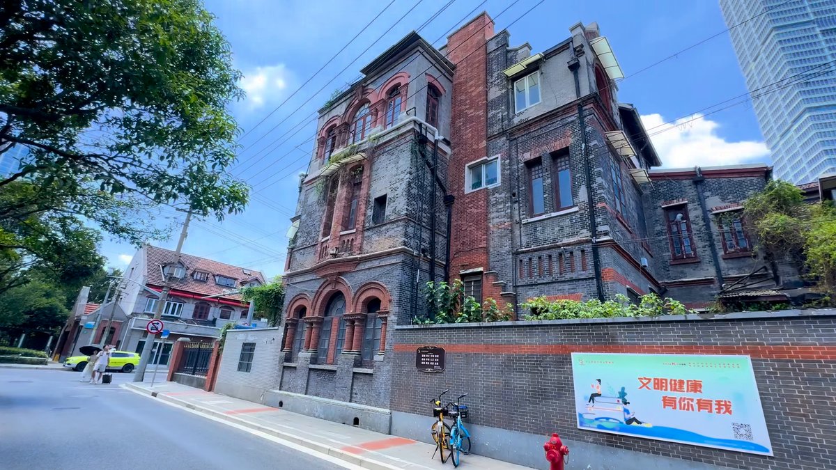 A weathered dark brick mansion on a street