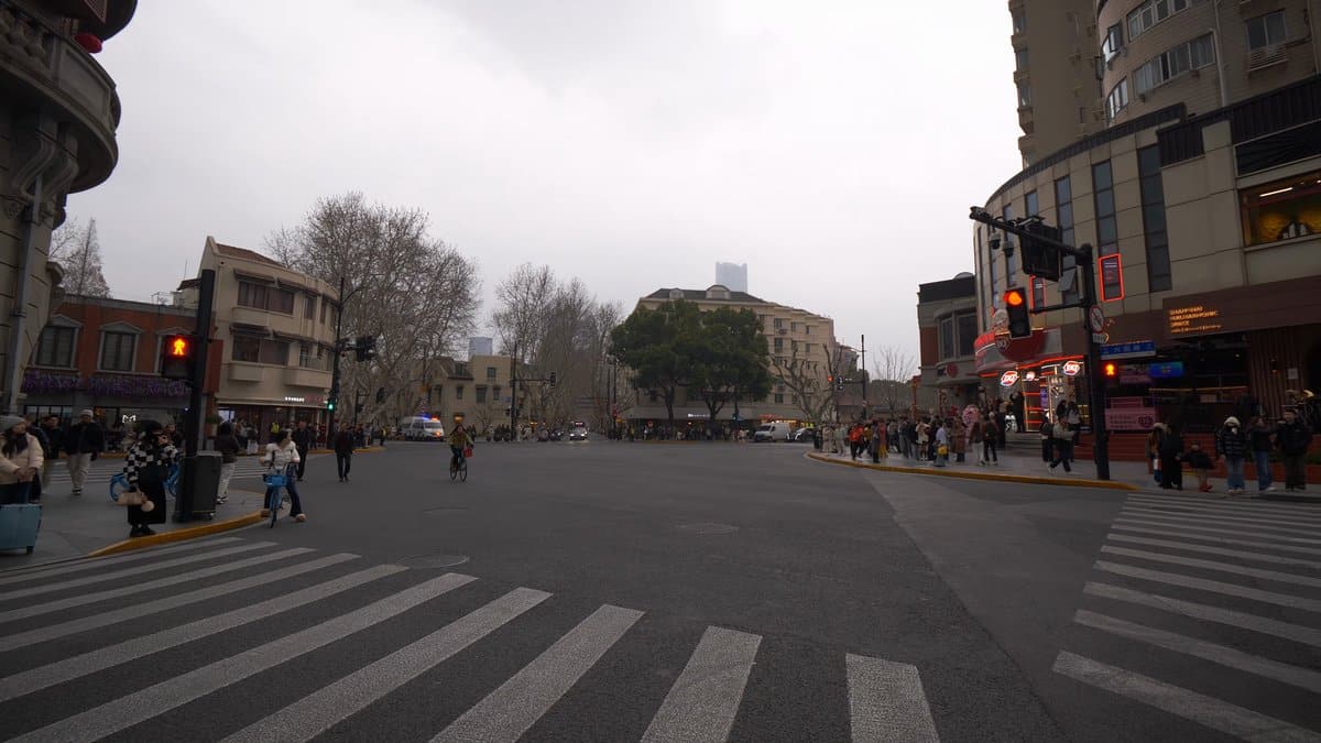 A wide intersection with a zebra crossing, pedestrians