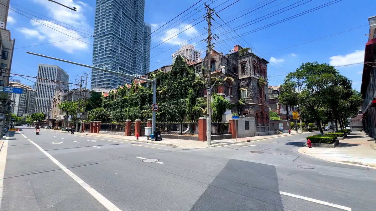 A wide junction with an ivy-covered historic building