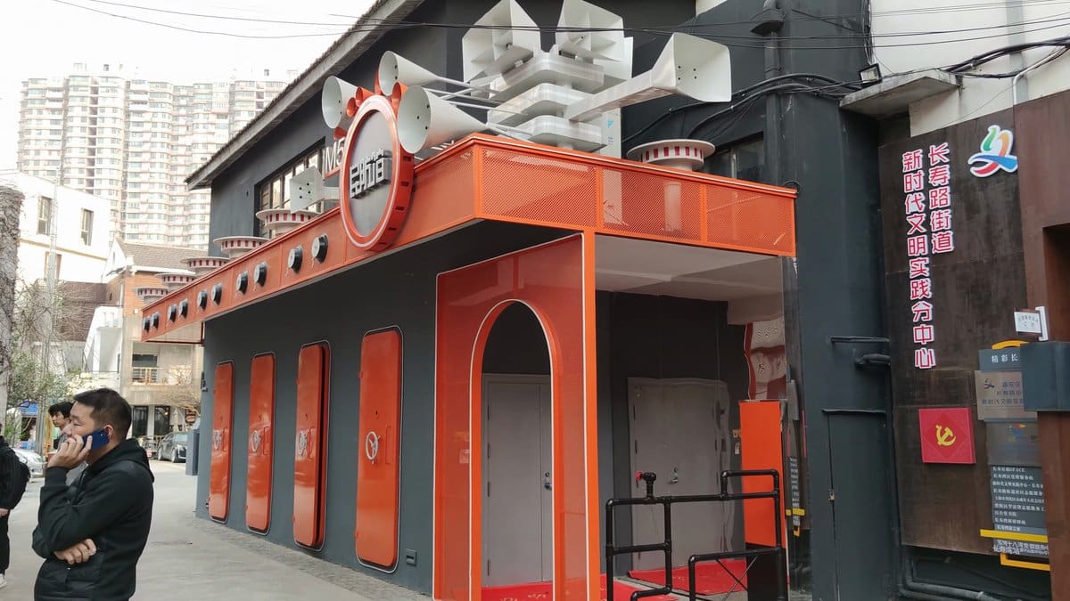 An orange-painted kiosk standing in the lane, a