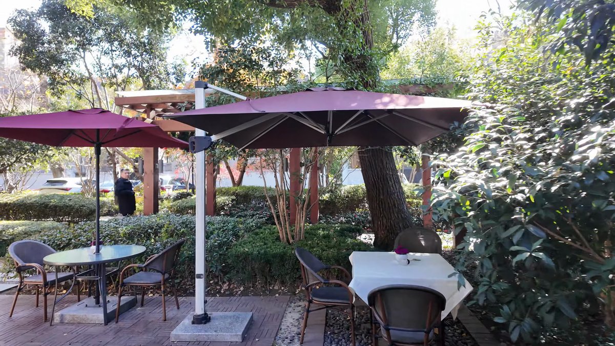 Cafe tables under a maroon parasol in a