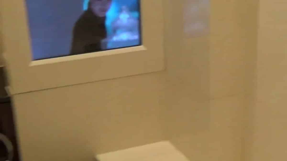 The bathroom television switched on, its picture glowing
