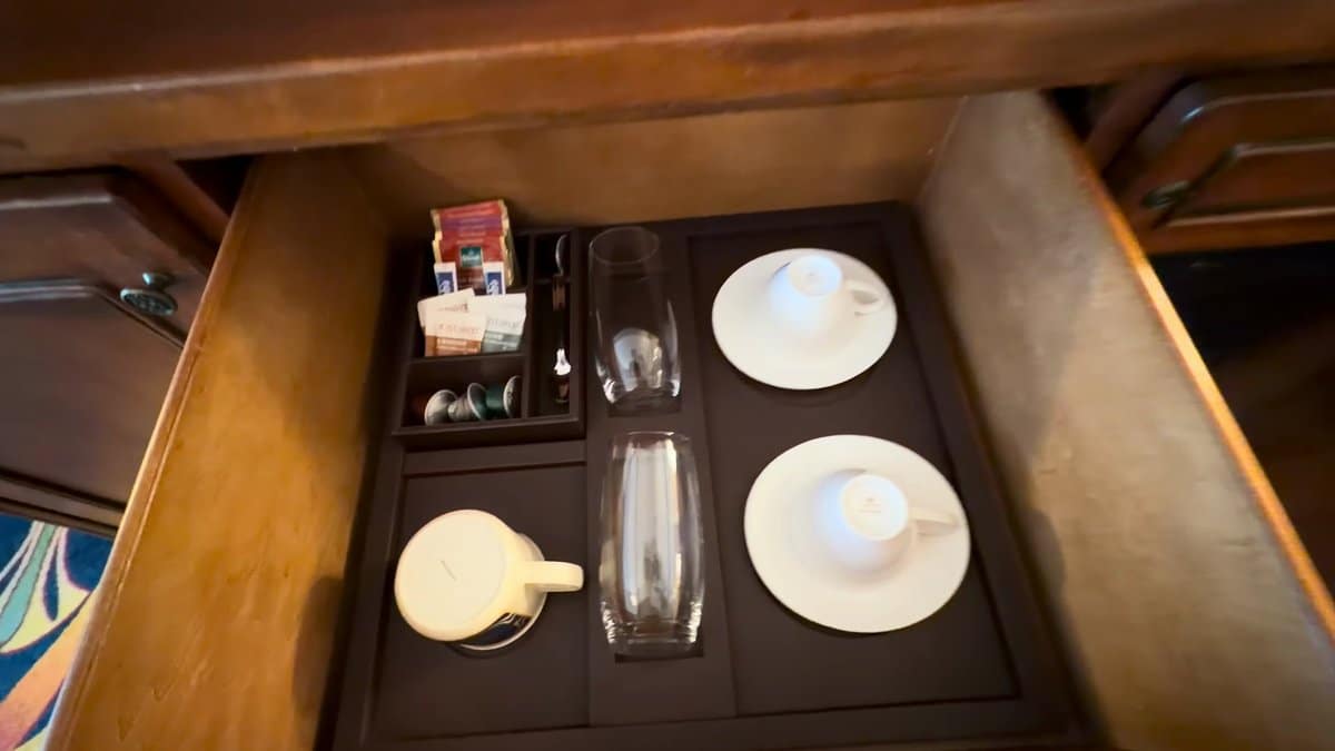 The cabinet drawer open on cups, tumblers, saucers
