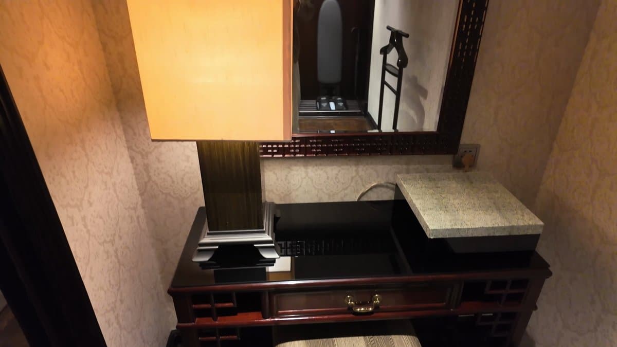 The desk under its lamp, a mirror above