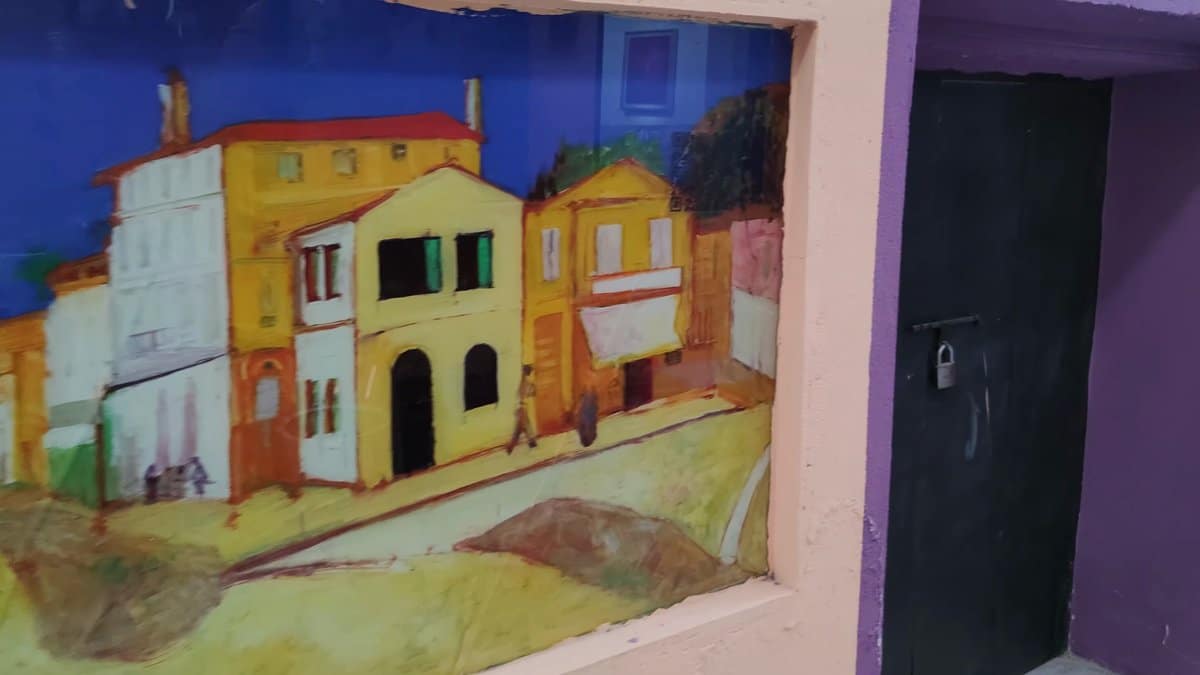 The painted village mural beside a dark doorway,