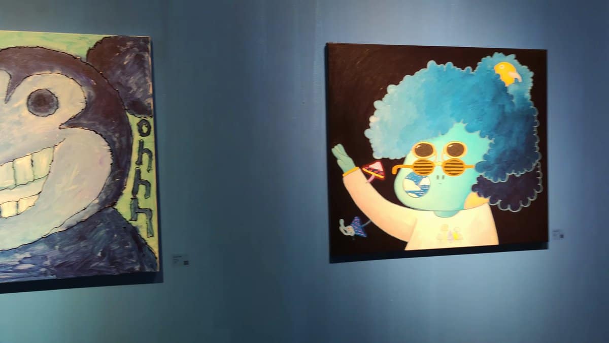 Two paintings hung on a deep blue wall,