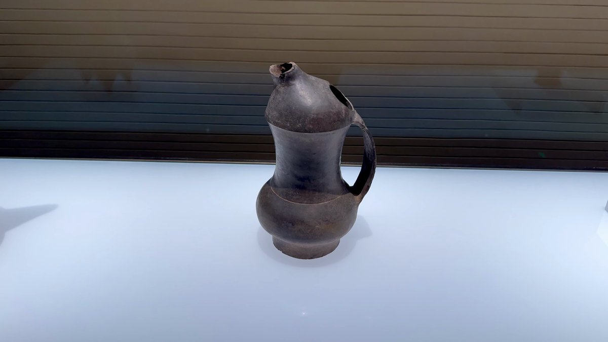 A black pottery jug with a curved spout
