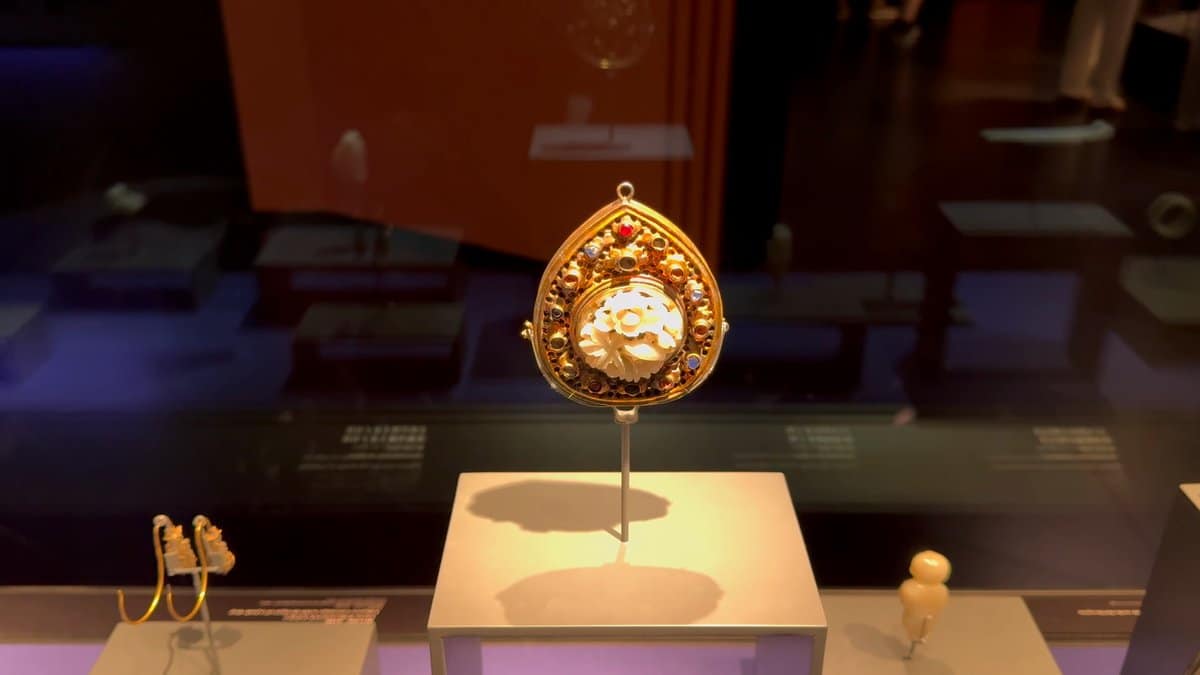 A gold pendant set with a pale stone,