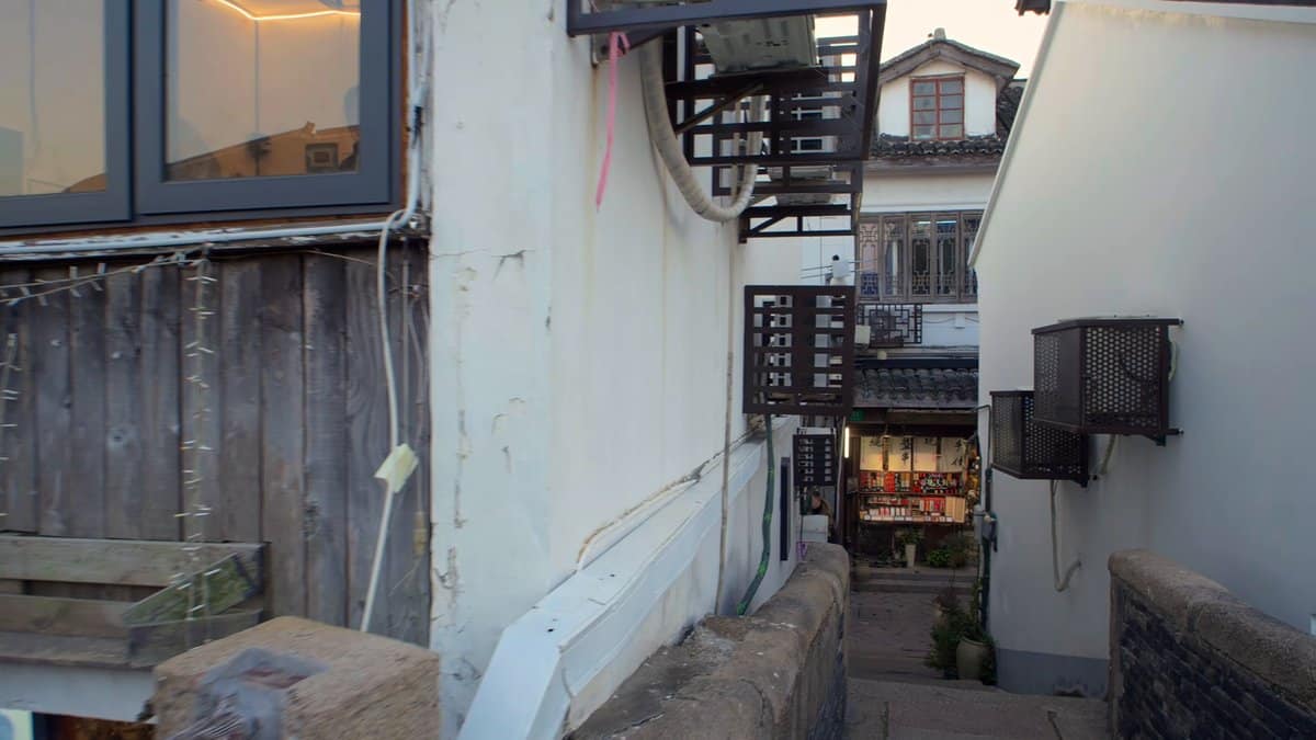 A white-walled alley beside an old timber building,
