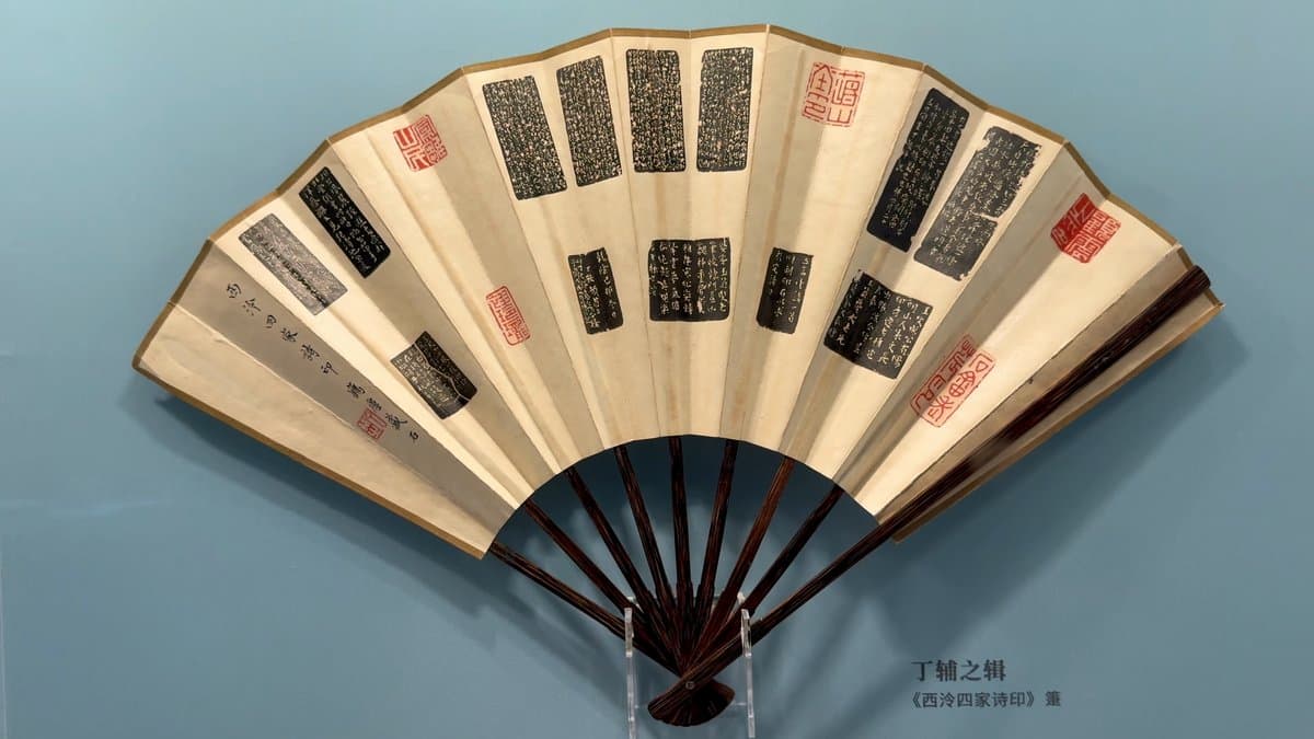 An open folding fan with blocks of calligraphy