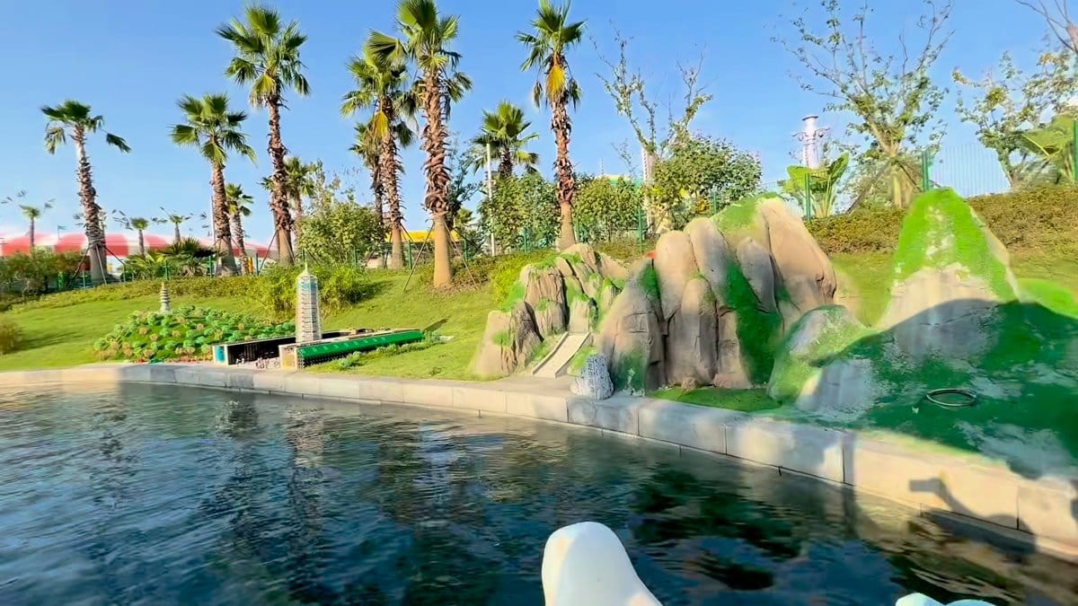 Palm trees and a green brick-built hill along