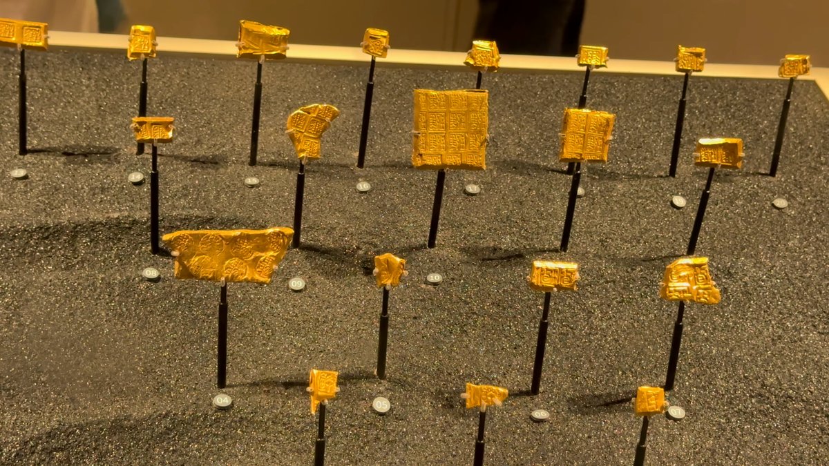 Small gold pieces mounted on pins over a