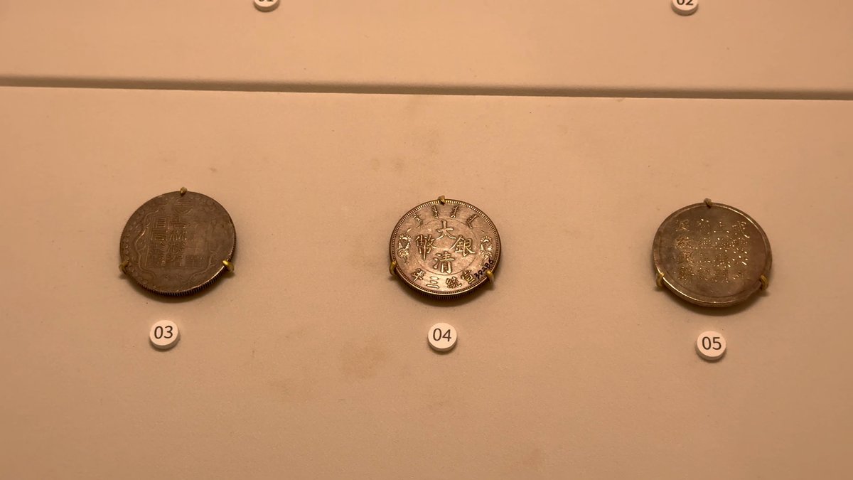 Three large silver coins numbered on the wall.
