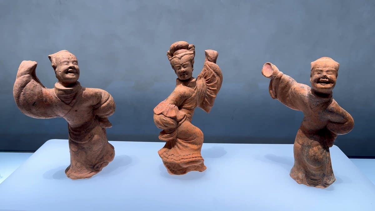 Three terracotta figures mid-dance